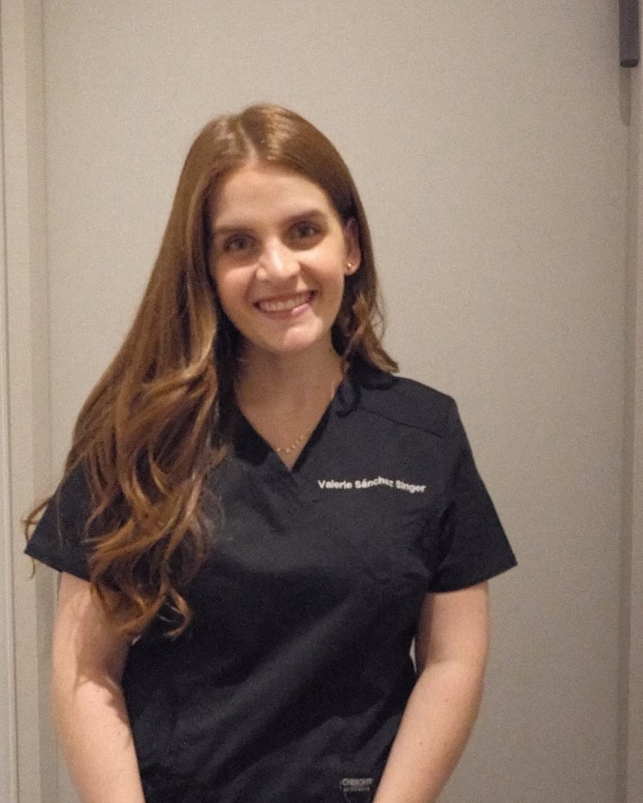 La Dra. Valerie sonriendo, con su uniforme negro de médica